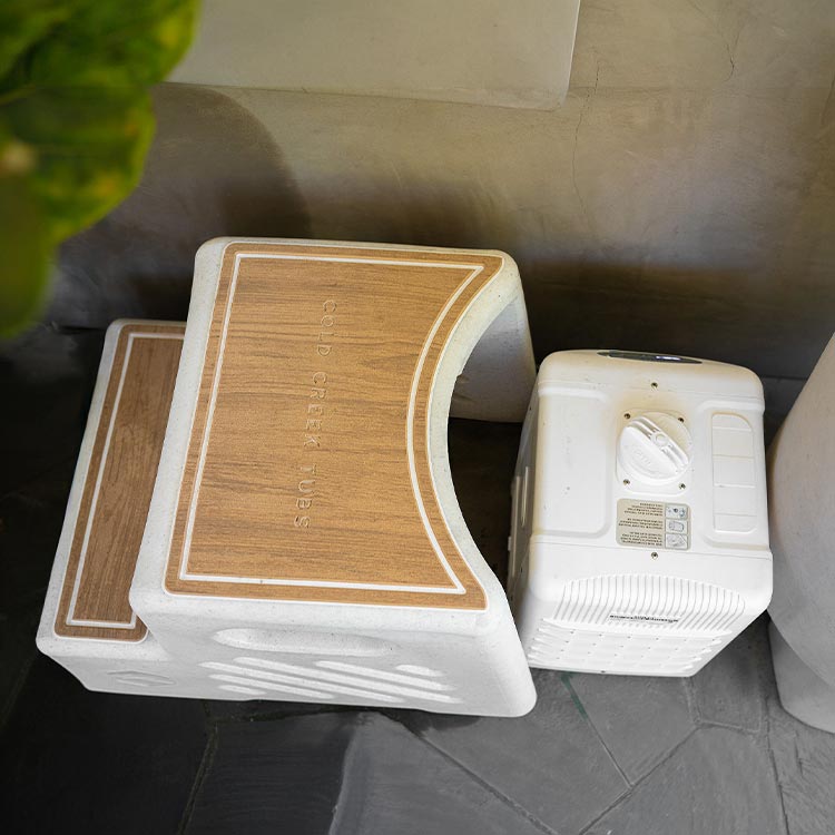 Two white step stools with wooden-like tops next to a cooling and filtration unit of a vertical tub