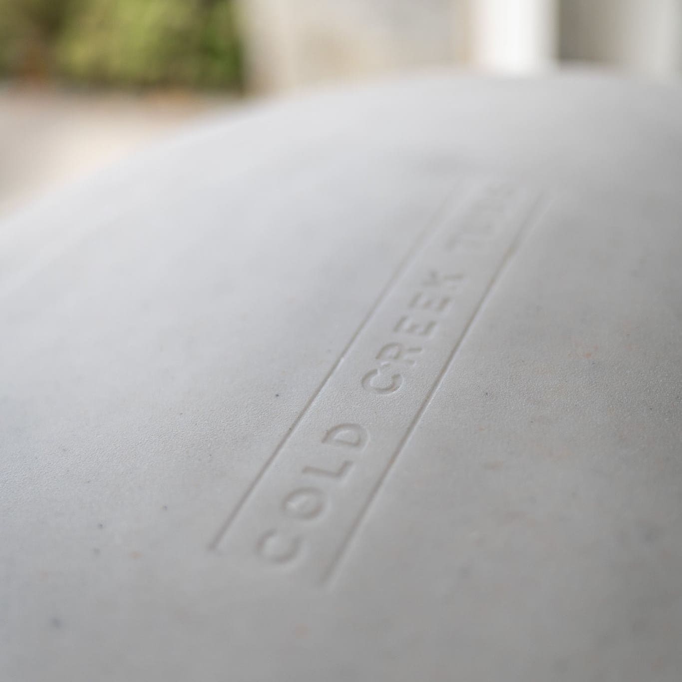 Close-up of a vertical tub with 'COLD CREEK' embossed on it, blurred background