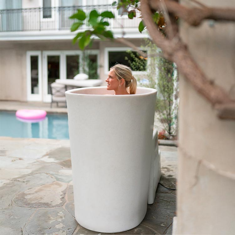Woman sitting in a vertical tub with a pool and house in the background