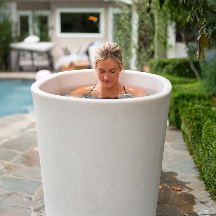 Woman in a vertical tub planter outdoors near a pool