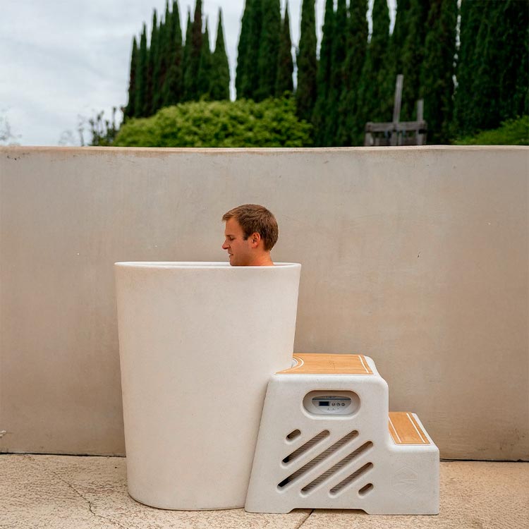 Man resting on a Vertical Tub with a concrete wall and trees in the background